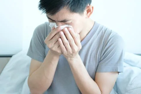 Sick man is flu, using a paper napkin and he have a runny nose. And he was co Stock Photos