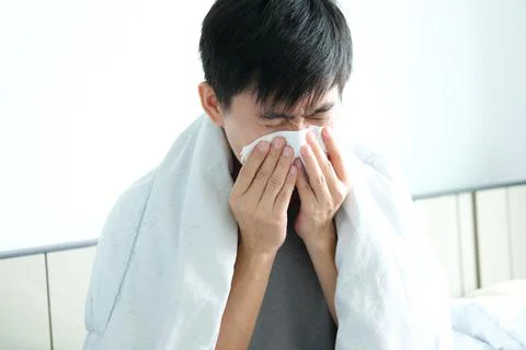 Sick man is flu, using a paper napkin and he have a runny nose. And he was co Stock Photos