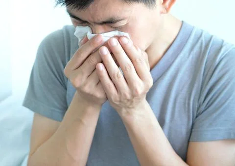Sick man is flu, using a paper napkin and he have a runny nose. And he was co Stock Photos