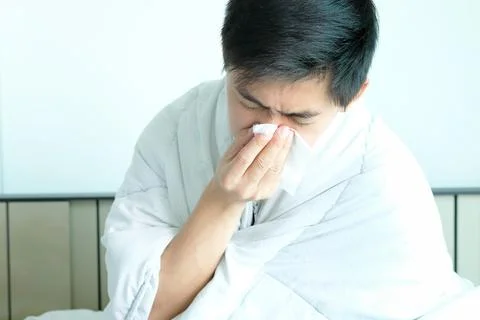 Sick man is flu, using a paper napkin and he have a runny nose. And he was co Stock Photos