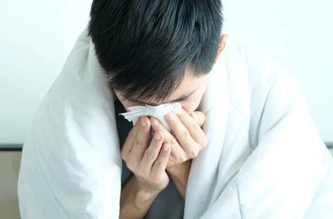 Sick man is flu, using a paper napkin and he have a runny nose. And he was co Stock Photos