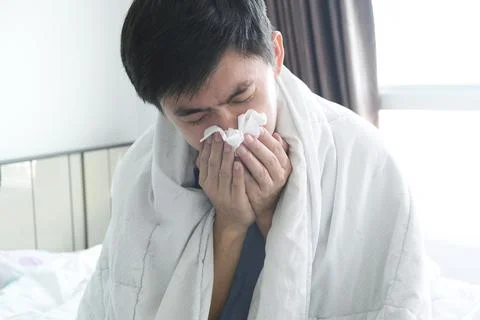 Sick man is flu, using a paper napkin and he have a runny nose. And he was co Stock Photos