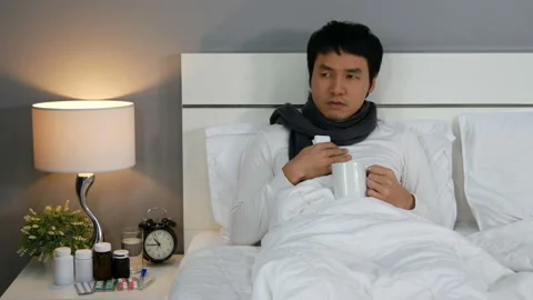 Sick man headache and drinking a cup of hot water on a bed Video stock 130726316