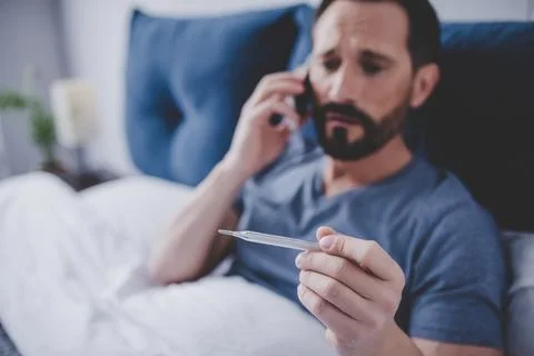 Sick man holding thermometer Stock Photos