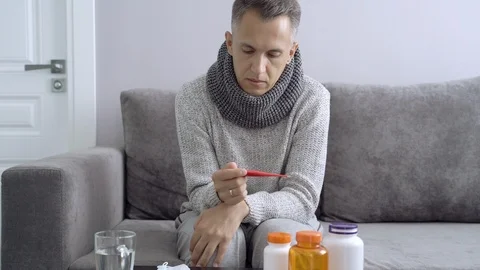 Sick man holding a thermometer sitting on the couch. Healthcare, medical concept Stock Footage 110806442