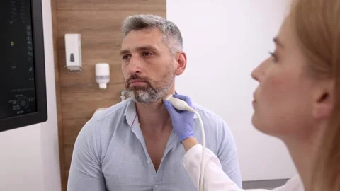 Sick man looking for causes of headache while getting ultrasound scan of neck Stock Footage 321001643
