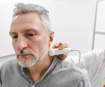 Sick man looking for causes of headache while getting ultrasound scan of ne.. Fotos de archivo