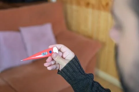 Sick man looking at the high temperature marked on the thermometer after Stock Photos