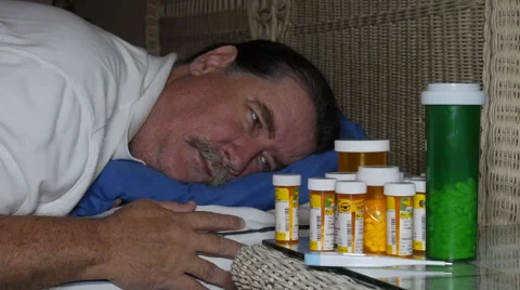 Sick man looking at many bottles of prescription pills Stock Footage 61293965