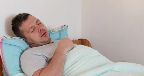 Sick man lying on bed and coughing a lot Stock Footage 165946336