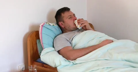Sick man lying on bed and coughing a lot Stock Footage 165946366
