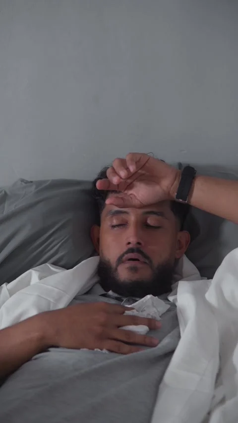 Sick man lying in bed with fever and sneezing Stock Footage 329124816