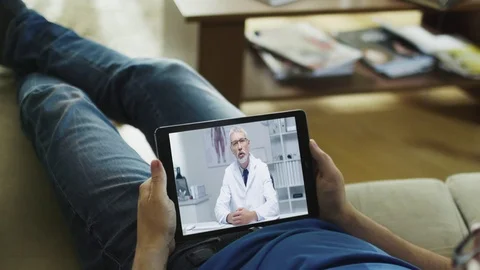 Sick Man Lying on a Couch and Having Video Conversation with His Doctor Stock Footage