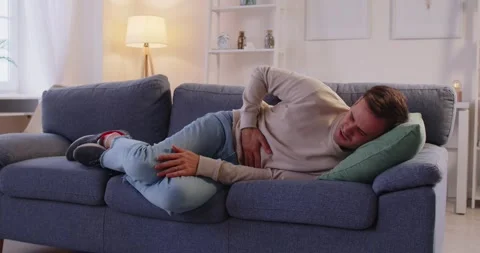 Sick man lying on sofa, touching belly in suffer from stomach ache, ill 스톡 동영상 305094450