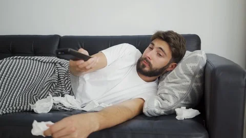 Sick man lying on sofa watching TV Stock Footage 119309024