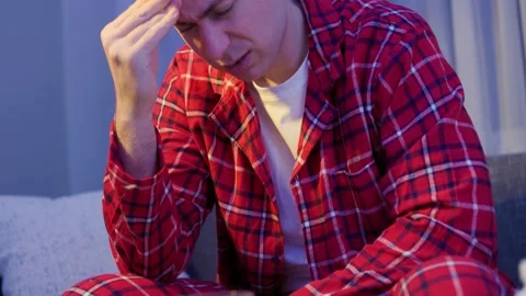 Sick man in pajamas suffering from cold and flu symptoms, feeling unwell with he Stock Footage 341880826