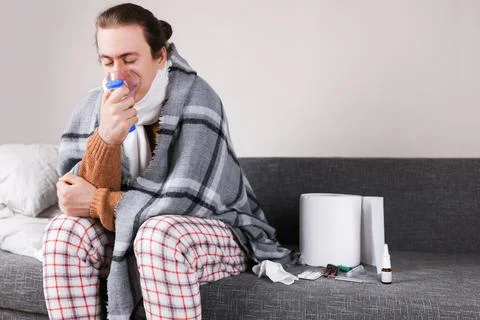Sick man in pajamas using nebulizer mask for respiratory treatment while si.. Stock Photos