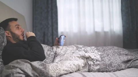 Sick man playing video games from bed. Addicted gamer playing video games during Video stock 129305819