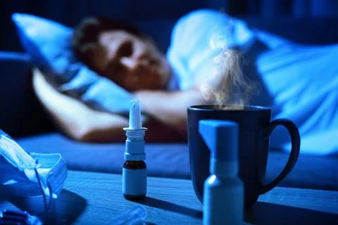 Sick man is resting in bed with a cold and flu illness. In the foreground, .. Stock Photos