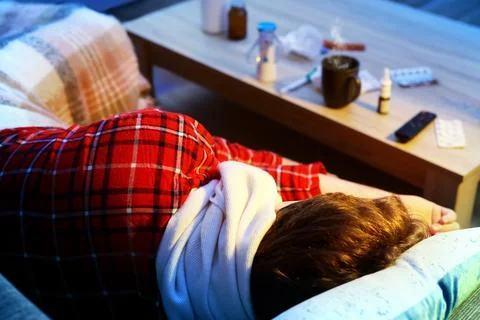 Sick man resting on a couch with a cold and flu illness. Feeling unwell, he.. Stockfoto's