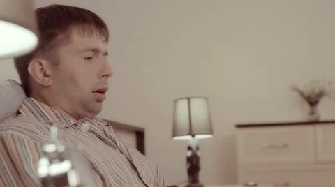 Sick man sitting in bed and blowing his nose in tissue. He feels bad Stockbeeldmateriaal 68429145