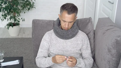 Sick man taking pills sitting on couch at home Stock Footage 111753686