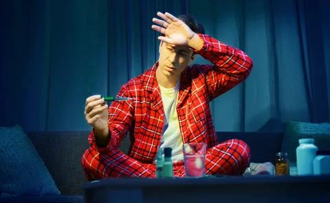 Sick man touching his forehead checking high fever from cold and flu. Home .. Stock Photos