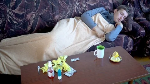 Sick man under blanket sleeping on couch Stock Footage 118911430