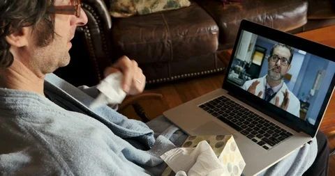 Sick man using a laptop computer for a telemedicine appointment with his doctor Video stock 120653018