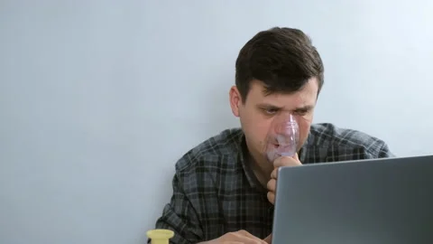 Sick man is using nebulizer and inhaler for treatment cure working on laptop. Stock-Footage 153712141