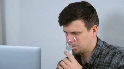Sick man is using nebulizer and inhaler for treatment cure working on laptop. Stock Footage 153767707