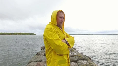 Sick man in a yellow raincoat on a stone pier 스톡 동영상 89882618