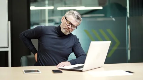 Sick mature gray haired bearded businessman in glasses has back pain while sit Stock Footage 232580925