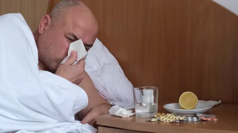Sick mature man lying on bed at home and blowing nose Stock Footage 301894151