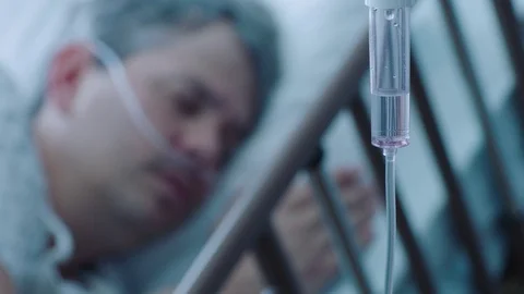 A sick middle aged man with an IV drip recovering in a hospital bed, slow Video stock 74396936
