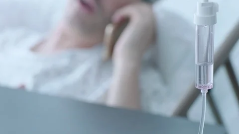 A sick middle aged man with an IV drip talking on the phone in a hospital bed, Stock Footage 74400261