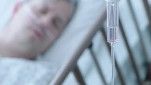 A sick middle aged man with an IV drip recovering in a hospital bed, slow Stock Footage 74400507