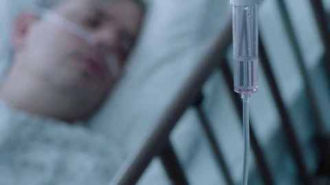 A sick middle aged man with an IV drip recovering in a hospital bed, slow Stock Footage 74400536