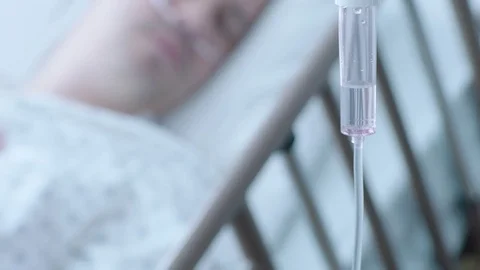 A sick middle aged man with an IV drip recovering in a hospital bed, slow Stock Footage 74401143