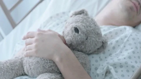 A sick middle aged man on oxygen holding a teddybear in a hospital bed, slow Stock Footage 74389322