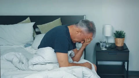 A sick middle-aged man suffers from a headache at home and goes to bed. Stock Footage 169716133