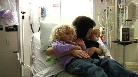 Sick Mother hugging children in hospital bed for a visit