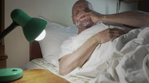 Sick old man lies in bed and wants to drink glass of water Video stock 237239792