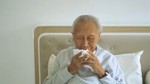 Sick old man sneezing with a tissue on bed Video stock 113053014