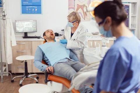 Sick patient sitting on dental chair with open mouth Stock Photos