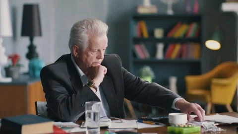Sick senior man sitting at table at home looking at pills sad and depressed Stock Footage 127631873