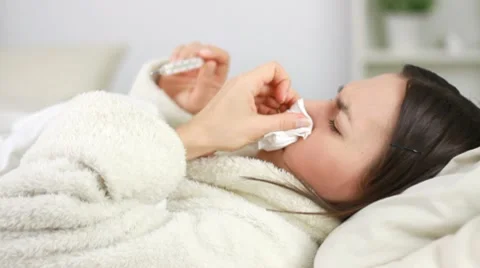 Sick woman in bed checking her temperature and blowing nose HD Stock Footage 10302574