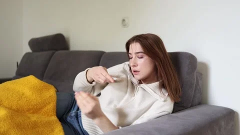 Sick woman checking thermometer on sofa Vidéo 336246526