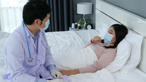 Sick woman lying in a bed while doctor checking her pulse Stock Footage 130960736