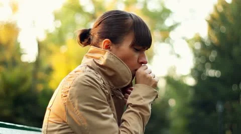 Sick woman sitting on park bench and coughing Stock Footage